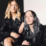 Chic fashion portrait of two young women in leather coats, posing with confidence and attitude.